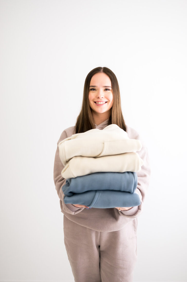 Woman holding stack of Comrt sweatsuits